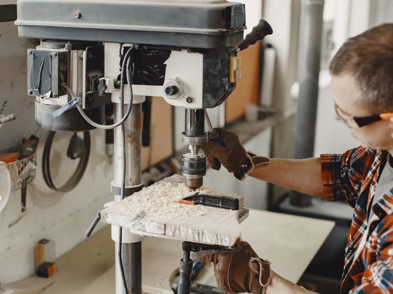 Wood cutting with circular saw. Closeup of mature man sawing lumber.